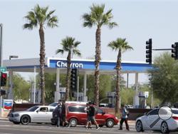 People walk by a gas station and convenience store hours after police surrounded the location near Interstate 10, detaining a person of interest and seizing the man's white Chevrolet Tahoe early on Friday, Sept. 11, 2015, raising hopes of a resolution to the rash of freeway shootings rattling the metro area in Phoenix. (AP Photo/Ross D. Franklin)