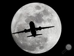 An airplane crosses a nearly full-moon on its way to Los Angeles International Airport near Whittier, Calif., Thursday, Dec. 24, 2015. Not since 1977 has a full moon dawned in the skies on Christmas. (AP Photo/Nick Ut)