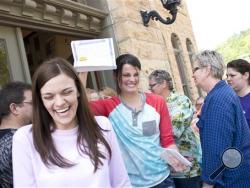 Kristin Seaton, center, of Jacksonville, Ark., holds up her marriage license as she leaves the Carroll County Courthouse in Eureka Springs, Ark., with her partner, Jennifer Rambo, left, of Fort Smith, Ark. Saturday, May 10, 2014, in Eureka Springs, Ark. Rambo and Seaton were the first same-sex couple to be granted a marriage license in Eureka Springs. (AP Photo/Sarah Bentham)