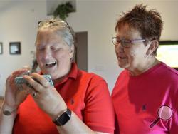 April Miller, left, and her partner Karen Roberts read the decision of the United States Sixth Circuit Court of Appeals refusing to hear Rowan County Clerk Kim Davis' appeal ordering her to issue marriage licenses because of her religious beliefs in Morehead, Ky., Wednesday, Aug. 26, 2015. (AP Photo/Timothy D. Easley)