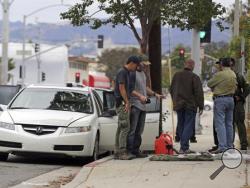 Investigators view items removed from a car, left, after a heavily armed man was arrested in Santa Monica, Calif., early Sunday, June 12, 2016. The man reportedly told police he was in the area for West Hollywood's huge gay pride parade. Authorities did not know of any connection between the gay nightclub shooting in Orlando, Fla., early Sunday and the Santa Monica arrest. (AP Photo/Reed Saxon)