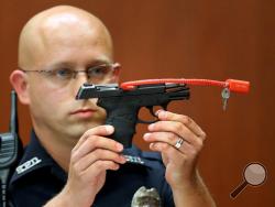 In this June 28, 2013, file photo, Sanford police officer Timothy Smith holds up the gun that was used to kill Trayvon Martin, while testifying in the George Zimmerman trial, in Seminole circuit court in Sanford, Fla. The pistol former neighborhood watch volunteer Zimmerman used in the fatal shooting of Martin is going up for auction online. (AP Photo/Orlando Sentinel, Joe Burbank, Pool, File)