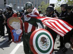 Erik Lopez, dressed as "Captain Mexico", stands in front of police officers while protesting Republican presidential candidate Donald Trump outside of the Hyatt Regency hotel during the California Republican Party 2016 Convention in Burlingame, Calif., Friday, April 29, 2016. (AP Photo/Eric Risberg)