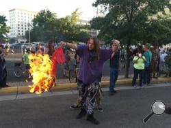 A protestor of Republican presidential candidate Donald Trump holds a burning T-shirt as hundreds of people protest outside a rally for Trump in Albuquerque, Tuesday, May 24, 2016. (AP Photo/Russell Contreras)