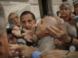 Pensioners try to get a number to enter inside a bank in Athens, Wednesday, July 1, 2015. About 1,000 bank branches around the country were ordered by the government to reopen Wednesday to help desperate pensioners without ATM cards cash up to 120 euros ($134) from their retirement checks. (AP Photo/Daniel Ochoa de Olza)
