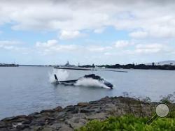 In this image taken from video provided by Shawn Winrich, a helicopter crashes near Parl Harbor, Hawaii on Thursday, Feb. 18, 2016. The private helicopter with five people aboard crashed and sunk into the water, leaving a teenage passenger in critical condition. (Shawn Winrich via the AP)