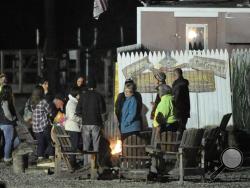 People gather around a fire at Harvest Hill Farms after a hayride accident that injured multiple people Saturday, Oct. 11, 2014, in in Mechanic Falls, Me. Police in Maine confirm a teen has died and two remain in critical condition after the crash. At least 20 other passengers were taken to area hospitals for treatment. (AP Photo/Maine Today, Gabe Souza) 