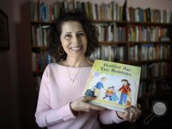 n this Wednesday, March 11, 2015 photo, author Leslea Newman, of Holyoke, Mass., displays a copy of her book "Heather Has Two Mommies," in Holyoke. (AP Photo/Steven Senne)