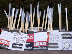 FILE - Placards are gathered together at the close of a picket by members of The Writers Guild of America outside Walt Disney Studios, Tuesday, May 2, 2023, in Burbank, Calif. On Sunday, Sept. 24, 2023, a tentative deal was reached to end Hollywood’s writers strike after nearly five months. (AP Photo/Chris Pizzello, File)
