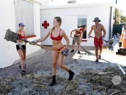 Jacksonville Beach lifeguard Cami Wight shovels sand with other current and former lifeguards Saturday, Oct. 8, 2016, as they help clean up after the Jacksonville Beach, Fla., lifeguard station took on sand and water during the storm surge that preceded Hurricane Matthew passing by the Jacksonville area. (Bob Self/The Florida Times-Union via AP)