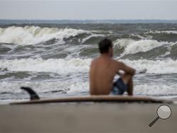 Eric Dunn sit on the northern end of Tybee Island's beach watching larger than average waves roll in as a result of approaching Hurricane Matthew, Tuesday, Oct. 4, 2016 in Tybee Island, Ga. Hurricane Matthew was on track to rake Florida before spinning up the East Coast. The Category 4 storm packing winds of 145 mph pummeled parts of Haiti and the Dominican Republic on Tuesday and is expected to head north over Cuba and the Bahamas before nearing the Florida coast by Thursday. (Josh Galemore/Savannah Mornin