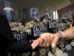 Protesters clasp hands in front of a line of California National Guard, Monday, June 9, 2025, at a Federal Building in downtown Los Angeles. (AP Photo Jae Hong)