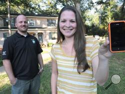 Angela Dalton shows her iPhone that she accidentally dropped out of an airplane over Dothan, Ala. and landed in the front yard of Eric Hall, left, Tuesday, Oct. 1, 2013. (AP Photo/The Dothan Eagle, Danny Tindell) 