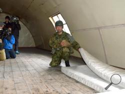 A member of the Self-Defence Forces shows the mattress which the 7-year-old Japanese boy who went missing nearly a week ago, was using insidide a building in a military drill area in Shikabe town, on the northernmost main island of Hokkaido Friday, June 3, 2016. The boy, missing since Saturday, was found unharmed Friday, police said, in a case that had set off a nationwide debate about parental disciplining. (Risa Ominato/Kyodo News via AP)