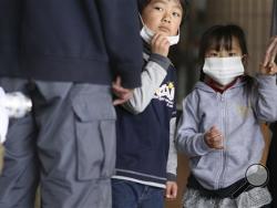 In this March 29, 2011 file photo, children watch their father being screened for radiation at a shelter in Fukushima, northeast of Tokyo. (AP Photo/Wally Santana, File)