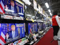 A salesclerk stands in front of flat-panel TVs showing Republican's front-runner candidate Donald Trump in a news program on the U.S. presidential election's Super Tuesday at an electronics store in Tokyo, Wednesday, March 2, 2016. (AP Photo/Shizuo Kambayashi)