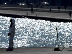 A lone woman creates a social media video along Lake Michigan Monday, Feb. 26, 2024, in Chicago. A warm front is sweeping spring-like weather across a large swath of the country in what is usually one of the coldest months of the year. The rare warmup is sending people out of their homes to enjoy the winter respite but also bringing increased wildfire danger. (AP Photo/Charles Rex Arbogast)