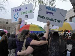 Two protesters hold up signs against passage of legislation in North Carolina, which limits the bathroom options for transgender people, during a rally in Charlotte, N.C., Thursday, March 31, 2016. The rally drew around 100 people at the Charlotte-Mecklenburg Government Center. (AP Photos/Skip Foreman)
