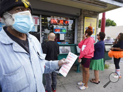 Philip Smith, wears a face mask and gloves as he lines up to purchase his lottery tickets for the Powerball lottery at the Blue Bird Liquor store in Hawthorne, Calif., Monday, Oct. 31, 2022. The jackpot for Monday night's drawing soared after no one matched all six numbers in Saturday night's drawing. It's the fifth-largest lottery jackpot in U.S. history. (AP Photo/Damian Dovarganes)