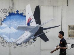 In this Tuesday, Feb. 23, 2016, file photo, a waiter walks past a mural of flight MH370 in Shah Alam outside Kuala Lumpur, Malaysia. Malaysia's government said Thursday, May 12, 2016, that two more pieces of debris, discovered in South Africa and Rodrigues Island off Mauritius, were "almost certainly" from Flight 370, which mysteriously disappeared more than two years ago with 239 people on board.(AP Photo/Joshua Paul, File)