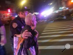 A police officer escorts an injured man away from the scene of a possible explosion on West 23rd Street in New York. Authorities said dozens suffered minor injuries. (AP Photo/Nico Maounis)
