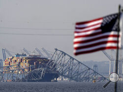 An American flag flies on a moored boat as the container ship Dali rests against wreckage of the Francis Scott Key Bridge, Tuesday, March 26, 2024, as seen from Pasadena, Md. (AP Photo/Mark Schiefelbein)