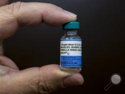 In this Thursday, Jan. 29, 2015 photo, pediatrician Charles Goodman holds a dose of the measles-mumps-rubella, or MMR, vaccine at his practice in Northridge, Calif. (AP Photo/Damian Dovarganes)