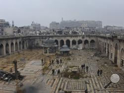This photo released by the Syrian official news agency SANA, shows Syrian troops and pro-government gunmen marching walk inside the destroyed Grand Umayyad mosque in the old city of Aleppo, Syria, Tuesday, Dec. 13, 2016. Government forces and rebel fighters have fought to control the 12th century mosque in the last four years, until Syrian troops seized control of it this week. Syrian rebels said Tuesday that they reached a cease-fire deal with Moscow to evacuate civilians and fighters from eastern Aleppo, 