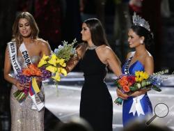 Former Miss Universe Paulina Vega, center, takes away the flowers and sash from Miss Colombia Ariadna Gutierrez, left, before giving them to Miss Philippines Pia Alonzo Wurtzbach, right, at the Miss Universe pageant on Sunday, Dec. 20, 2015, in Las Vegas. Gutierrez was incorrectly named the winner before Wurtzbach was given the Miss Universe crown. (AP Photo/John Locher)