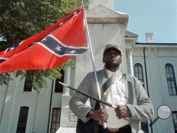  In this May 8, 2000, file photograph, Anthony Hervey holds a Confederate flag while standing underneath the Confederate monument in Oxford, Miss. (Bruce Newman/The Oxford Eagle via AP, File)