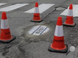 In this Tuesday, June 10, 2014 photo, a pothole filled by mosaic artist Jim Bachor on a street in Chicago is protected by cones until it is ready to be driven on. Bachor has filled seven potholes around the city and marks each one with a mosaic piece. (AP Photo/Stacy Thacker)