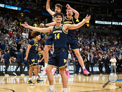 Michigan guard Ian Burns, front, joins forward Will Tschetter and guard Charlie May in celebrating after defeating Texas A&M in the second round of the NCAA college basketball tournament Saturday, March 22, 2025, in Denver. (AP Photo/John Leyba)