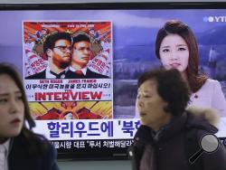 In this Monday, Dec. 22, 2014, file photo, people walk past a TV screen showing a poster of Sony Picture's "The Interview" in a news report, at the Seoul Railway Station in Seoul, South Korea. (AP Photo/Ahn Young-joon, File)