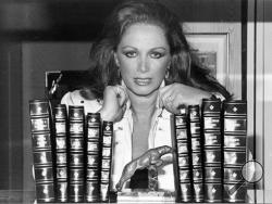 In this July 19, 1984 file photo, author Jackie Collins poses with her books at her home in Beverly Hills, Calif. Collins, died in Los Angeles on Saturday, Sept. 19, 2015, of breast cancer. She was 77. (AP Photo, File)