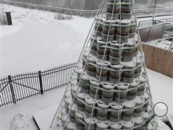 A two-story Christmas tree made of 300 half-barrel beer kegs lights up the sky outside the Genesee Brew House in downtown Rochester, N.Y. on Wednesday, Dec. 10, 2014. The keg tree is trimmed with 600 feet of green lights and topped by a rotating Genesee sign. More than 20 of Genesee's "elves" also known as employees, got to work designing and building the keg tree. (AP Photo/Democrat & Chronicle, Shawn Dowd)