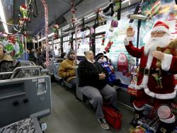 In this photo made with a fisheye lens, passengers sit among some of the Christmas theme decorations on the transit bus decorated by driver Bill Sanfilippo for the holiday season on Wednesday, Dec. 9, 2015, in Pittsburgh. Sanfilippo has been decorating his bus since he was hired as a driver 10 years ago by the Port Authority of Allegheny County. (AP Photo/Keith Srakocic)