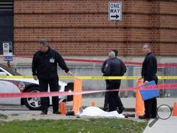 Police cover the body of a suspect outside Watts Hall on the campus of Ohio State University in Columbus, Ohio, following an attack on campus that left several people injured on Monday, Nov. 28, 2016. The man, identified as Abdul Razak Ali Artan, plowed his car into a group of pedestrians and began stabbing people with a butcher knife Monday before he was shot to death by a police officer. (Adam Cairns/The Columbus Dispatch via AP)