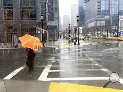 FILE - A person braces against the wind as a wintry mix of snow and rain falls in Boston, March 14, 2023. A winter weather system moving through the U.S. is expected to wallop the East Coast this weekend, Saturday, Jan. 6, 2024, into Sunday, Jan. 7, with a mix of snow and freezing rain from the southern Appalachians to the Northeast — although it's too early to say exactly which areas will get what precipitation and how much. (AP Photo/Michael Casey, File)