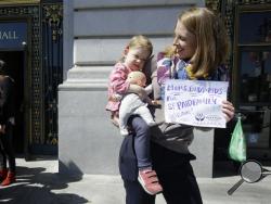 Kim Turner holds her daughter Adelaide Turner Winn before a rally supporting paid family leave at City Hall in San Francisco, Tuesday, April 5, 2016. The San Francisco Board of Supervisors is voting on whether to require six weeks of fully paid leave for new parents - a move that would be a first for any jurisdiction. (AP Photo/Jeff Chiu)