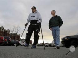 ReWalk Robotics service engineer Tom Coulter, right, looks on as paralyzed Army veteran Gene Laureano walks using a ReWalk device Wednesday, Dec. 16, 2015, in Bronx, N.Y. The Department of Veterans Affairs has agreed to pay for robotic legs that could allow scores of paralyzed veterans with spinal cord injuries to walk again. (AP Photo/Mel Evans)