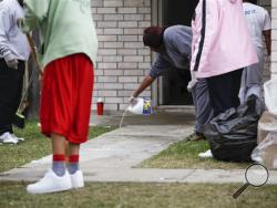 Tonya Grice uses hydrogen peroxide Sunday, Nov. 10, 2013 to clean blood from the walkway of her sister's house where two people were killed and at least 16 others wounded late Saturday when gunfire erupted at a house party in the Cypress area, authorities said. The shooting broke out about 11:15 p.m. in the 7300 block of Enchanted Creek Drive, in Houston.(AP Photo/Houston Chronicle, Eric Kayne)