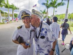 In this Monday, Dec. 5, 2016 photo, about 30 Pearl Harbor Survivors with the "Greatest Generation" vets meet and greet with visitors at the Pearl Harbor Visitor Center in Honolulu. Lt. Dawn Stankus, left, was there to help escort the Pearl Harbor survivors and Edward W. Stone, right, suddenly gave her a kiss and said I hope you don't mind. Which Stankus said "it was an honor to be kissed by you." On Wednesday, Dec. 7, thousands of servicemen and women and members of the public are expected to attend the 75t