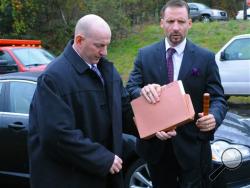 Mark Kessler, left, suspended police chief, arrives with his attorney Joseph Nahas, right, for his public hearing involving his termination notice on Thursday, Oct. 10, 2013, in Gilberton, Pa. The hearing for Kessler, who made profanity-laced Internet videos about liberals and the Second Amendment, was halted Thursday after a handgun belonging to one of his supporters slid out of its holster and crashed onto the concrete floor. (AP Photo/Republican-Herald, Andy Matsko)