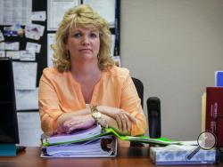 Deb Roschen poses for a photo in Rochester, Minn., on July 11, 2016, with notebooks of evidence of how authorities accessed information about her through law enforcement databases. The former county commissioner alleged in a 2013 lawsuit that law enforcement and government employees inappropriately ran repeated queries on her and other politicians over 10 years. The searches were in retaliation for questioning county spending and sheriff’s programs, she said. (AP Photo/Bruce Kluckhohn)