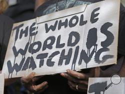 A man holds a sign during a protest for the shooting death of Walter Scott at city hall in North Charleston, S.C., Wednesday, April 8, 2015. Scott was killed by a North Charleston police officer after a traffic stop on Saturday. The officer, Michael Thomas Slager, has been charged with murder. (AP Photo/Chuck Burton)