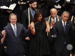 From left, former first lady Laura Bush, former President George W. Bush, first lady Michelle Obama and President Barack Obama join hands during a memorial service at the Morton H. Meyerson Symphony Center with the families of the fallen police officers, Tuesday, July 12, 2016, in Dallas. Five police officers were killed and several injured during a shooting in downtown Dallas last Thursday night. (AP Photo/Eric Gay)