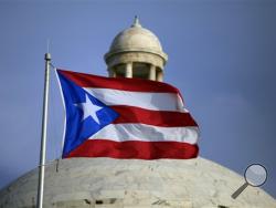 In this Wednesday, July 29, 2015 file photo, the Puerto Rican flag flies in front of Puerto Rico’s Capitol as in San Juan, Puerto Rico. Puerto Rico Gov. Alejandro Javier Garcia Padilla said on Sunday, May 1, 2016, that negotiators for the U.S. territory’s government have failed to reach a last-minute deal to avoid a third default and that he has issued an executive order to withhold payment. (AP Photo/Ricardo Arduengo, File)