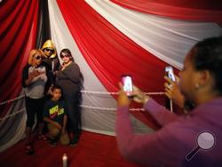 Lidianette Carmona, behind right, the wife of the late boxer Christopher Rivera, stands with Rivera's mother Celines Amaro, left, and Rivera's son Julio Christopher, as they pose for photos taken by fans with the body of Christopher Rivera propped up in a fake boxing ring during his wake at the community recreation center within the public housing project where he lived in San Juan, Puerto Rico.