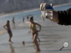 In this July 11, 2016 photo, doctoral candidate Rodrigo Staggemeier shows samples of water and sand from Copacabana Beach, collected for a study commissioned by The Associated Press, in Rio de Janeiro, Brazil. (AP Photo/Silvia Izquierdo)