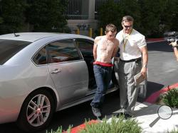 In this photo released by the Las Vegas Metropolitan Police Department, an unidentified police official leads Erich Nowsch, 19, from a car to police headquarters for questioning in Las Vegas, Thursday, Feb. 19, 2015. 